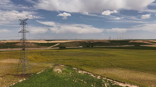 Power lines crossing rural landscape with vineyards and crops