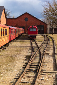 View of Aukstaitija narrow gauge railway with a red locomotive and passenger carriages parked at the depot in Panevezys, Panevezio apskritis, Lithuania.