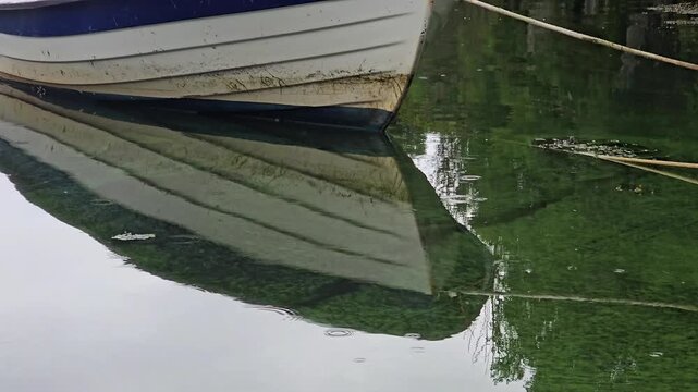Feflection of a wooden boat in seawater on a rainy day. Norway, Alver. August