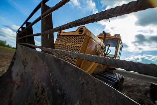 View of a yellow bulldozer blade in a field under a bright sky in Kelme, Siauliai County, Lithuania.