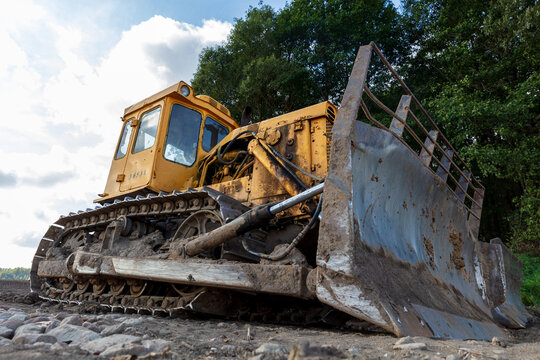 View of a yellow bulldozer on rocky ground near trees in Kelme, Siauliai County, Lithuania.