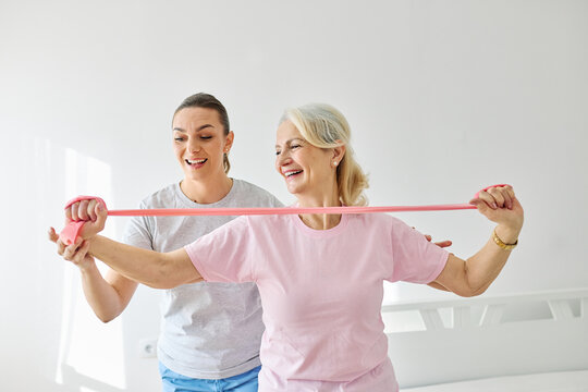 Doctor or nurse or physiotherapist caregiver exercise with senior woman at clinic or nursing home