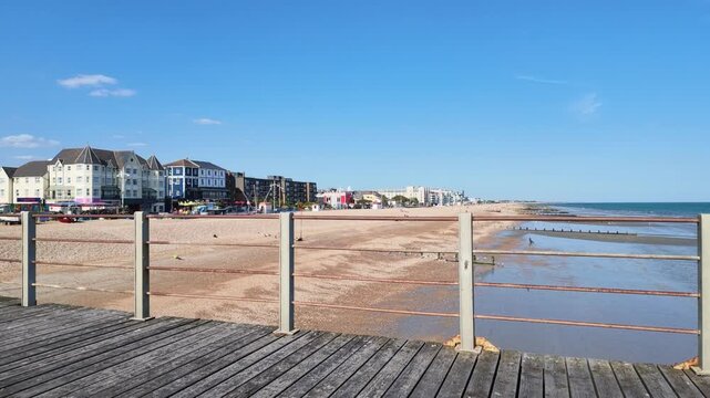 Bognor Regis West Sussex England UK. 14.07.2026. Video. A wide shot of a bustling pebble beach on a clear day, featuring diverse architecture and individuals relaxing by the sea at Bognor Regis 