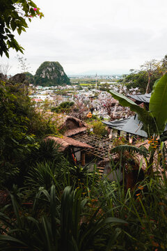 View of The Marble Mountains with lush tropical vegetation and traditional thatched-roof structures overlooking the town in Da Nang, Da Nang, Vietnam.