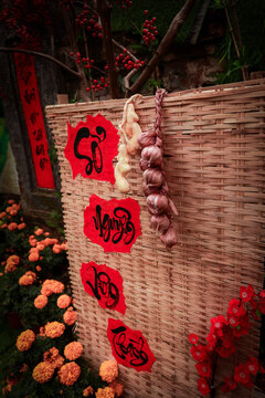 View of traditional Tet decorations featuring red calligraphy, garlic, and marigold flowers on a woven bamboo screen at The Marble Mountains, Da Nang, Da Nang, Vietnam.