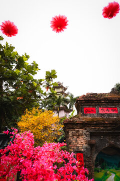 View of the historic brick entrance gate at The Marble Mountains, featuring vibrant pink flowers and a pagoda in the background in Da Nang, Da Nang, Vietnam.