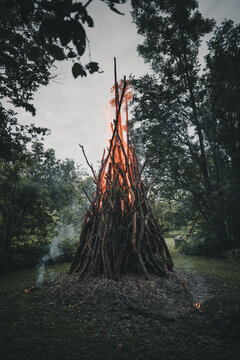 View of a traditional Midsummer bonfire burning brightly with tall flames and glowing embers in a forest clearing on Vormsi, Laane County, Estonia.