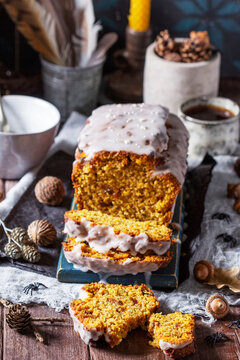 Pumpkin raisin bread with icing, served with tea on a dark background. Halloween concept.
