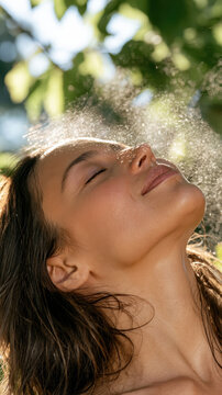 Woman closing her eyes while experiencing a refreshing facial mist spray, enjoying a moment of natural skincare, hydration, and wellness under dappled sunlight and green foliage
