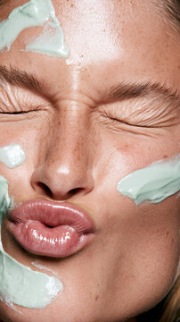 Person with eyes closed and puckered lips enjoying a green cosmetic face mask, embracing an aesthetic skin care routine and concept of clean beauty and natural wellness