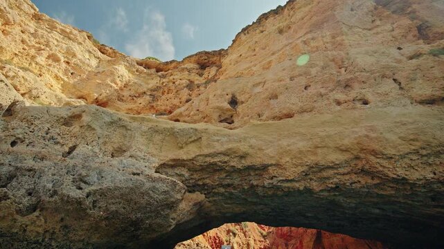 Weathered golden limestone cliffs and natural rock arch near Gruta do Paraiso in Carvoeiro, Algarve, Portugal.