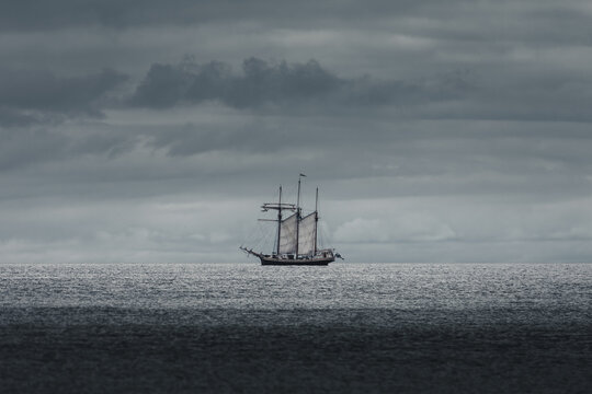 View of a sailing ship on the calm sea under a dramatic cloudy sky in Merikula, Harju maakond, Estonia.