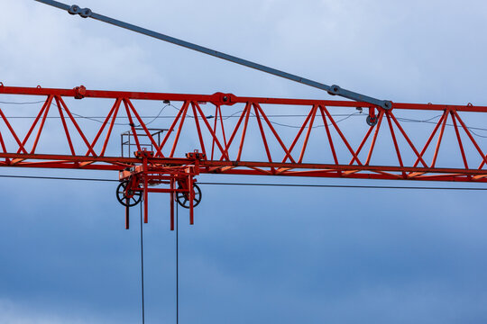 View of a red construction crane jib with a trolley and pulleys against a clear blue sky in Vilnius, Vilnius County, Lithuania.