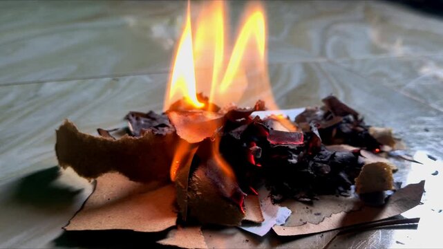 Fire Bright orange flame burning a piece of paper on a stone floor