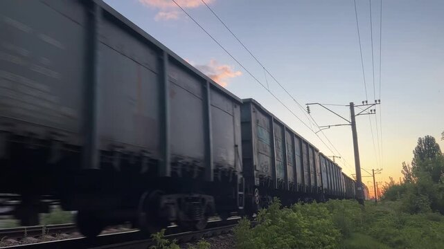 Freight Train Moving Fast on Railway Track at Sunset | Cargo Wagons Passing Wide Angle Low Perspective | Industrial Transportation and Logistics Concept