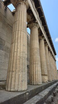 Athens, Greece - 8 July 2026. Side view of the Temple of Hephaestus in the Ancient Agora, with a row of Doric architectural columns, stone material flooring, and a Low Angle View.