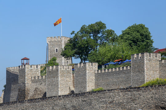 View of the historic stone walls and towers of Skopje Fortress with the North Macedonian flag flying under a clear blue sky in Skopje, Greater Skopje, North Macedonia.