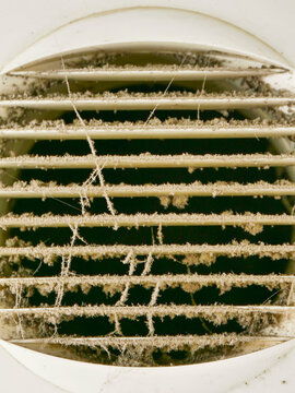 Dirty air vent with dust and cobwebs. Ventilation system needs cleaning. Grates covered in debris and filth. Dusty and neglected home or building feature. Not clean or maintained
