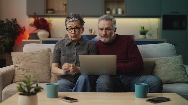 Couple in their 50s reading bad news email on laptop, rejected visa application