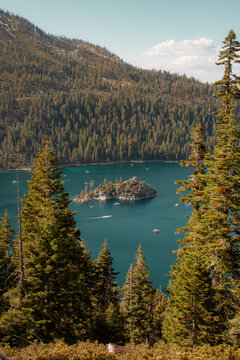 View of Fannette Island in Emerald Bay surrounded by deep blue water and dense pine forests under a clear summer sky, United States.