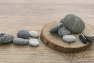 Obraz na płótnie Canvas Natural sea pebbles pile on round wooden slice background.