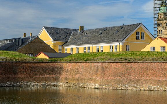 Historic yellow waterfront buildings behind brick fortress wall and moat.