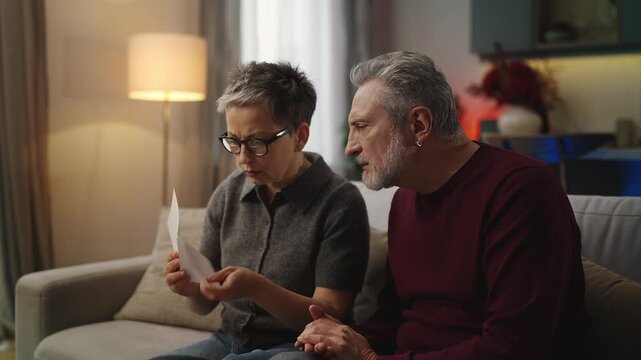 Middle-aged man and his wife reading bad news letter, disappointed about refusal