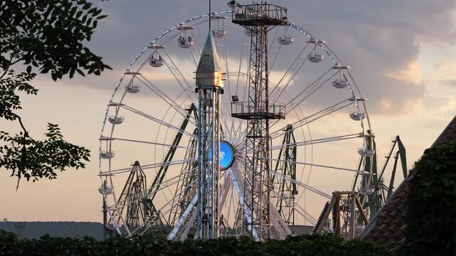 Ferris wheel spinning in amusement park at sunset