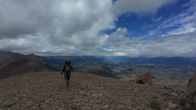 Hiker Trekking Across Rocky Mountain Summit In Cerro Castillo Patagonia Chile Under Dramatic Storm Clouds