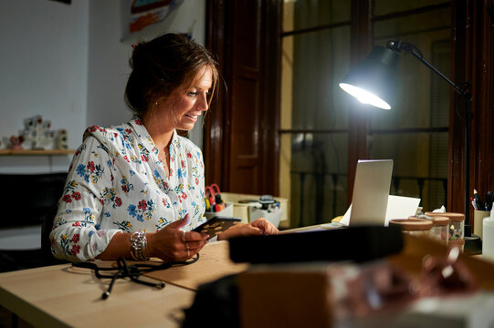 Woman working late night with laptop and smartphone