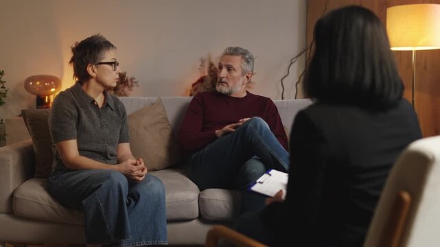 Middle-aged couple reconciling and while talking with counselor, saved marriage