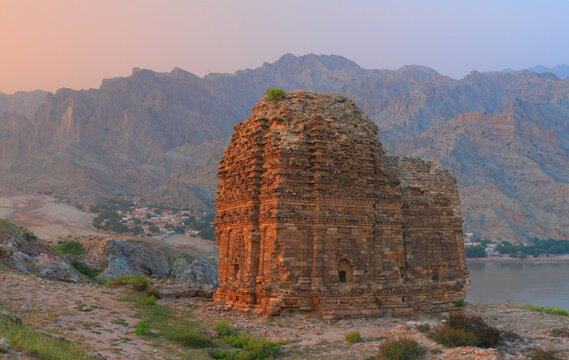 View of the ancient Mari Indus Temple from the Hindu Shahi period, standing on a rocky hill overlooking the Indus River with rugged mountains in the background, Kalabagh, Punjab, Pakistan.