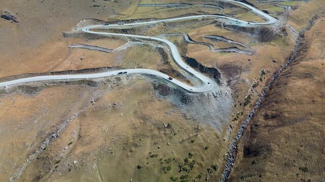 Aerial drone footage of the dramatic hairpin turns at Too-Ashuu Pass, Kyrgyzstan, featuring cars and trucks navigating one of the most spectacular mountain roads on the Bishkek&ndash;Osh Highway.