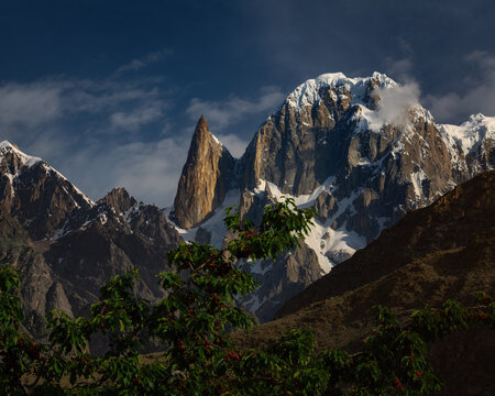 View of Lady Finger Peak rising above rocky slopes with a cherry tree in the foreground in Hunza Nagar, Gilgit Baltistan, Pakistan.