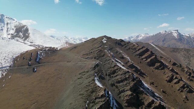 Aerial drone footage of the old mountain road at Too-Ashuu Pass, Kyrgyzstan, revealing abandoned switchbacks crossing the rugged Tian Shan landscape beside the modern Bishkek&ndash;Osh highway.