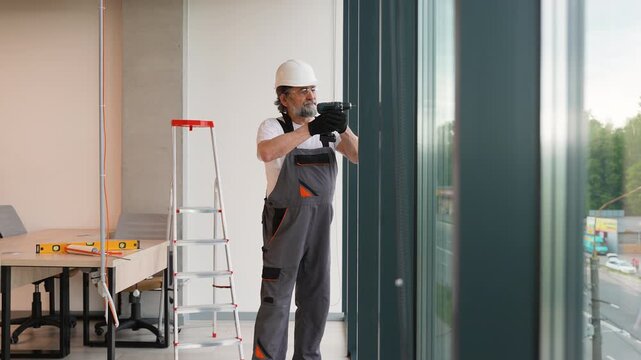 Mature construction worker installing window in a modern office building