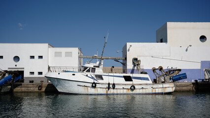 Fishing boat moored in a Mediterranean harbor in Altea, Spain, with white waterfront buildings and calm water for maritime travel and coastal industry themes © Jacek