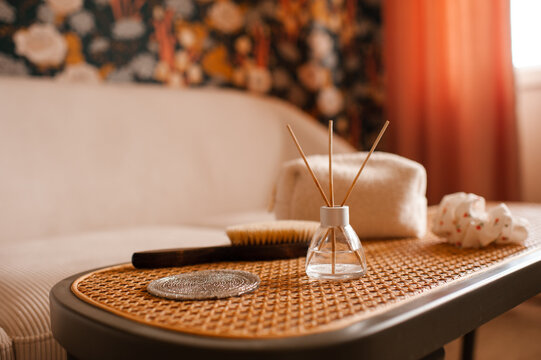 Home cozy atmosphere with liquid diffuser in glass bottle on rattan table close up in living room close up. Aromatherapy.