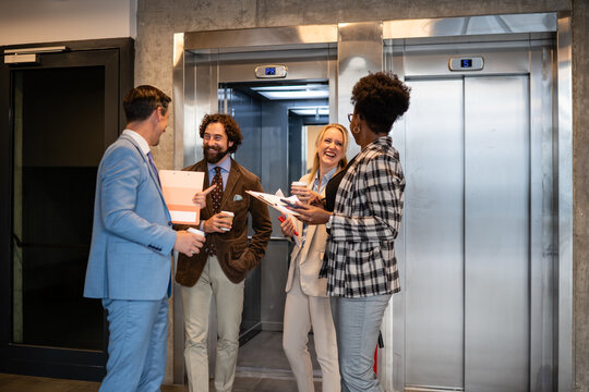 Business people networking and laughing in office elevator lobby