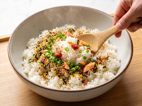 Wooden spoon scooping steamed rice with furikake seasoning in a bowl