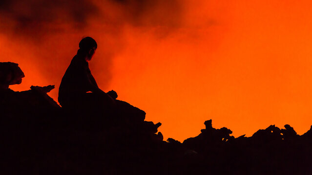 View of a person silhouetted against the glowing orange lava lake of Erta Ale volcano in Zone 2, Afar, Ethiopia.