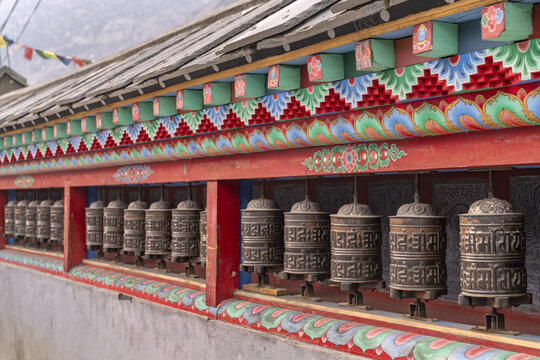View of the ornate prayer wheels at Tanki Manang with traditional painted wooden architecture in Manang, Gandaki Province, Nepal.