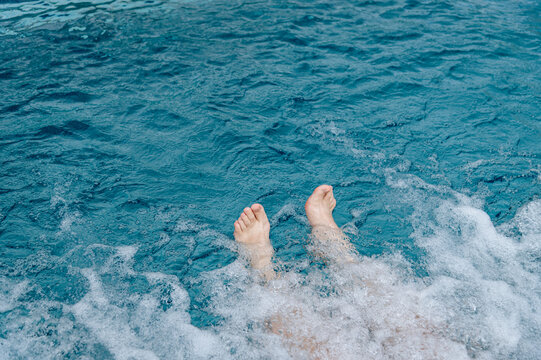 Feet splashing in water during a sunny day at a poolside