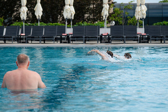 Families enjoy swimming in the pool at a hotel during the summer afternoon
