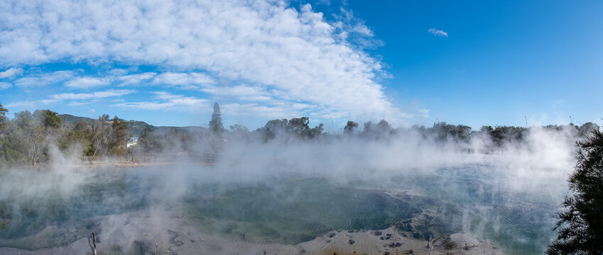 Kuirau Park, Rotorua, Leptospermum scoparium, Dampfender geothermaler See mit Sonnenstern am blauen Himmel, Neuseeland