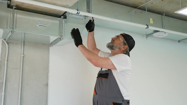 Professional plumber installing pipes on ceiling