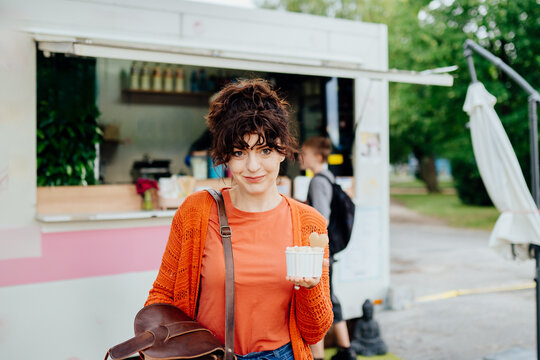 Confident woman holding rolled ice cream outside outdoor food truck