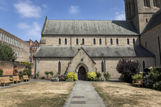 View of the Cathedral Church of St. Barnabas with its stone facade, arched entrance, and surrounding garden in Nottingham, England, United Kingdom.