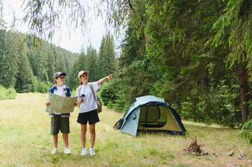 Fototapeta premium Kids exploring map and pointing in forest while camping