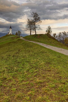 St.Primus and Felician hilltop Gothic church on a grassy ridge backed by the Karavanke mountains, on a cloudy autumn afternoon. Jamnik-Slovenia-174